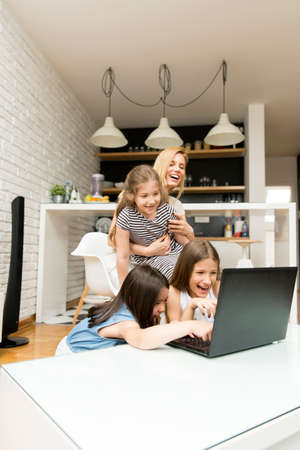 Woman with girls on the laptop at homeの写真素材