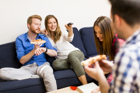 Group of friends eating pizza together at home