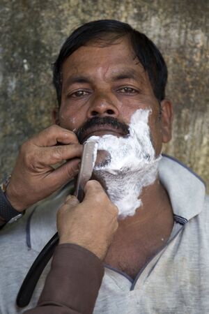 MUMBAI, INDIA - OCTOBER 10, 2015: Unidentified man being shaved at the barber shop in Mumbai, India. It is a local tradition.のeditorial素材