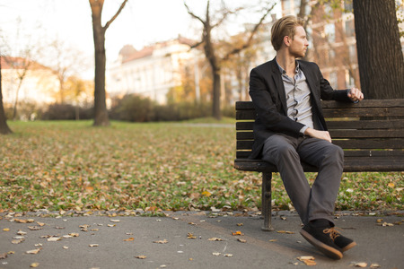 Young man on bench at autumn park