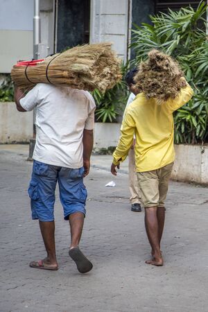 MUMBAI, INDIA - OCTOBER 9, 2015: Unidentified people carrying straw on the street of Mumbai, India. With 12 million people, Mumbai is the most populous city in India and the 9th most populous agglomeration in the world.のeditorial素材