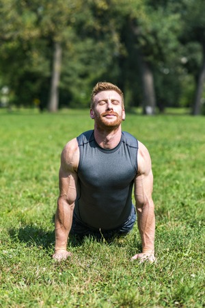 Young man doing exercises on the grass in the parkの写真素材