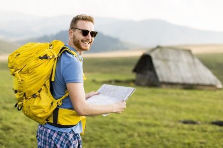 Young redhair man on mountain hiking holding a mapの写真素材
