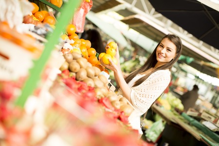 Young woman looking and buying fresh fruit at the marketの写真素材