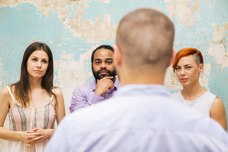 Young man speaks to other young people by grunge wallの写真素材