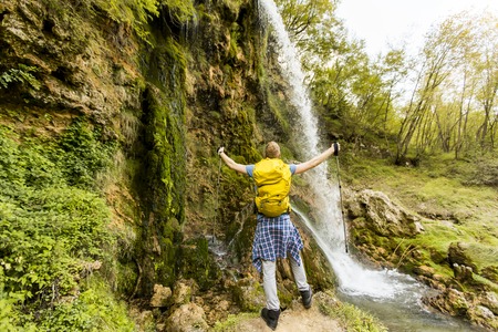 Young hiker stopped beside a mountain waterfall to restの写真素材