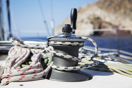 Young handsome sailor pulling rope on sailboat