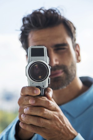 Handsome young man with old fashioned cameraの写真素材