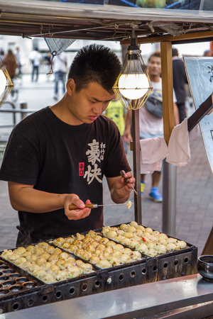 OSAKA, JAPAN . OCTOBER 9, 2016: Unidentified man preparing food on the street of Osaka, Japan. Osakai is known for its modern architecture, nightlife and hearty street food.のeditorial素材