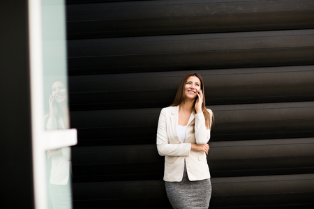 Beautiful young business woman calling by phone and smilingの写真素材