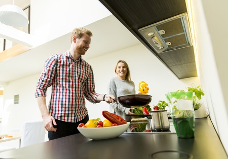 Happy young couple preparing food in the kitchenの写真素材