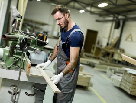 Young worker works in a factory for the production of furniture