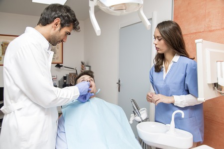 Young man having medical checkup in the dentist office by the young doctorの写真素材