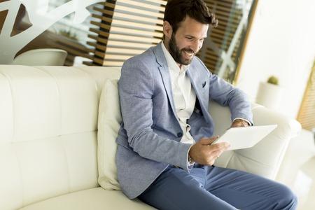 Young business man sitting and holding tablets in the handsの写真素材
