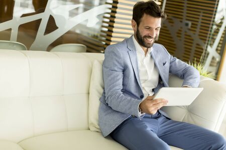 Young business man sitting and holding tablets in the handsの写真素材
