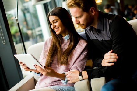 Young modern couple sitting together and using a tabletの写真素材
