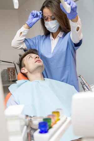 Young man having medical checkup in the dentist office by the young doctorの写真素材