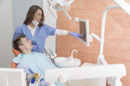 Young man having medical checkup in the dentist office by the young doctorの写真素材