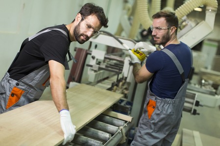 Young male workers work in a factory for the production of furnitureの写真素材