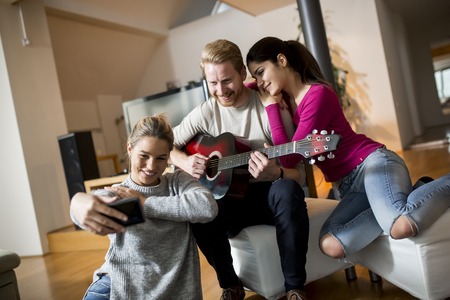 Young people having party with guitar in the roomの写真素材