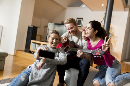 Young people having party with guitar in the roomの写真素材