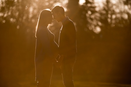 View at pregnant woman and man posing at autumn parkの写真素材