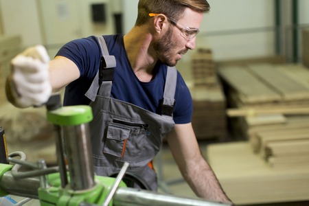 Young man works in a factory for the production of furnitureの写真素材