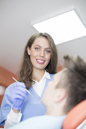 Young man having medical checkup in the dentist office by the young female doctorの写真素材
