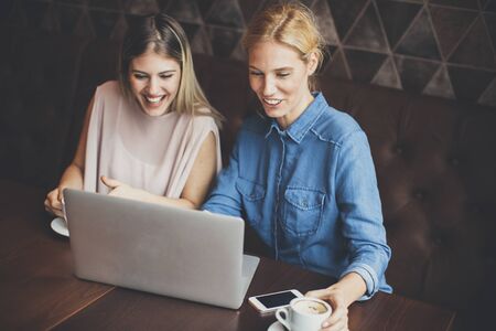 Two attractive young women with laptop in the cafeの写真素材
