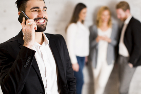 Handsome young businessman with mobile phone in the officeの写真素材