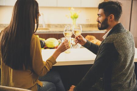 Happy couple toasting with white wine in the modern kitchenの写真素材