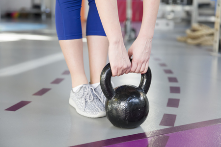 Young adult fitness woman doing  exercise with a kettlebell as a part of a fitness workout in gymの写真素材