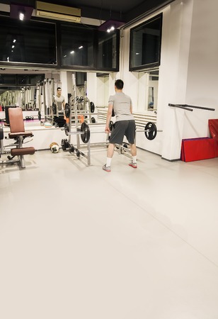 Young man weight lifting in the gymの写真素材