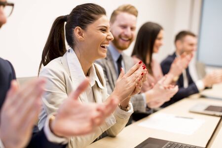 Young business people clapping their hands in office