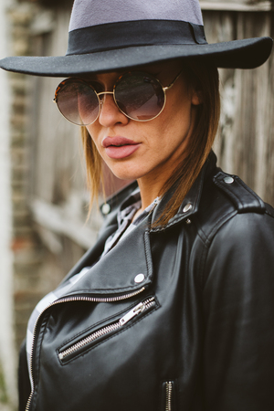 Attractive young woman with sunglasses by the wooden fenceの写真素材