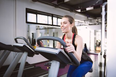 Smiling woman riding an exercise bike in gym