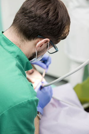 Close-up picture of young lady having her teeth examined by a dentist at dentist's officeの写真素材