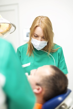 Young man on dental check-up  examined by female dentistの写真素材