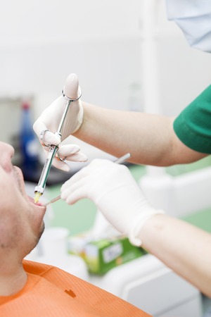 Female dentist provides dental anesthesia to patientの写真素材