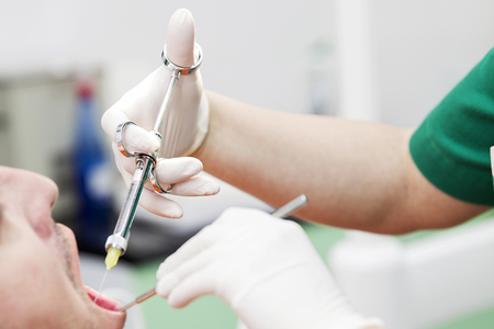 Female dentist provides dental anesthesia to patientの写真素材