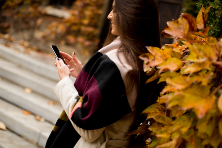Beautiful brunette woman using mobile phone outdoorの写真素材