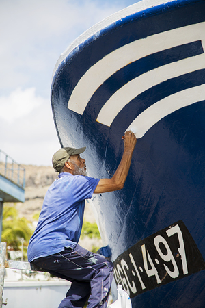 PUERTO DE MORGAN, SPAIN - MAY 3, 2016: Unidentified fisherman painting his boat in Puerto de Mogan, Gran Canaria, Spain. Puerto de Mogan is important fishing port.のeditorial素材