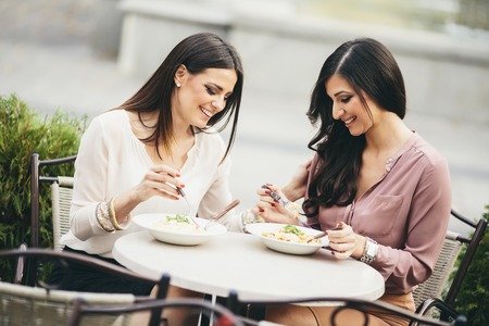 Pretty young women having lunch in the restaurant outdoorの写真素材