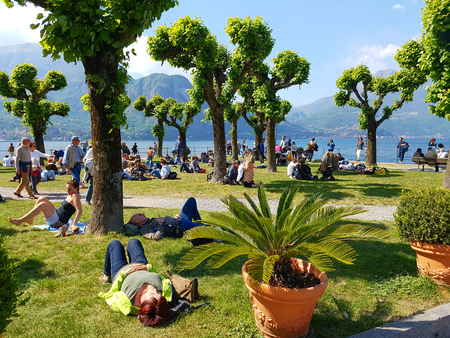 BELLAGIO, ITALY- APRIL 23, 2017: Unknown tourists lying on the grass by the lake Como in Bellagio, Italy. Bellagio is a very popular tourist destination.のeditorial素材