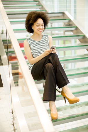 Smiling african american businesswoman using mobile phone in modern office