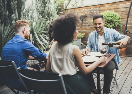 Cheerful young people have lunch in the courtyard and have a funの写真素材