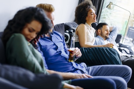Group of friends watching TV, drinking cider  and having fun in the roomの写真素材
