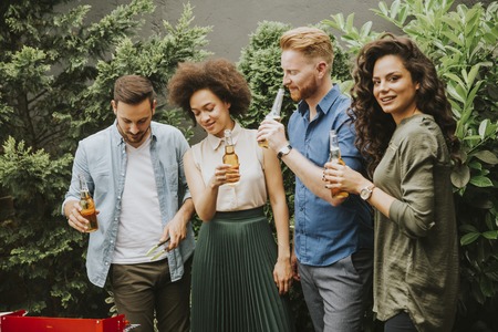 View at happy friends grilling food and enjoying barbecue party outdoorsのeditorial素材