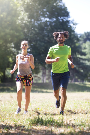 View at young couple running in the park on a sunny dayの写真素材