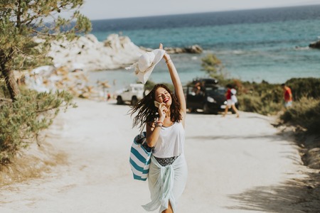 Pretty young woman with a bag on the beach at sunny summer dayの写真素材